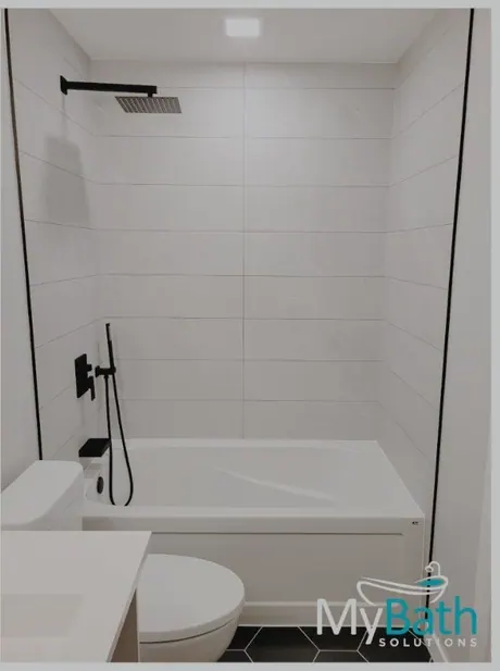 The same Calgary bathroom after: marble-look tile-less walls and black fixtures