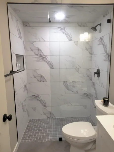 Walk-in shower with white marble-look tile-less walls and a grey mosaic floor, Calgary