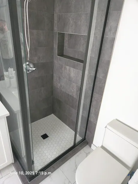 Dark tile-look shower with a recessed niche and hex-pattern floor, Calgary