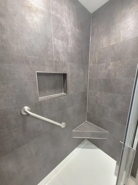Low-threshold shower with a built-in corner seat and dark slate-look walls, Calgary