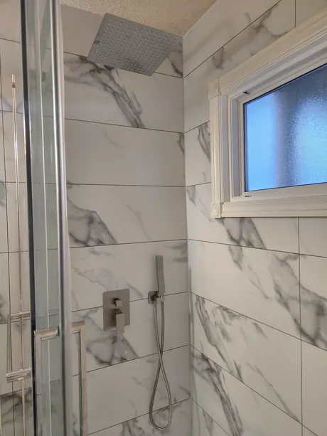 Marble-look shower with a rain head and a window in the wet wall, Calgary