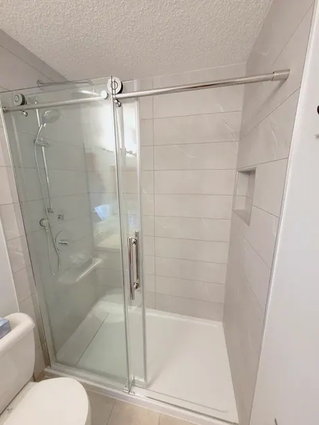 Shower with marble-look walls, recessed niche and sliding glass doors, Calgary