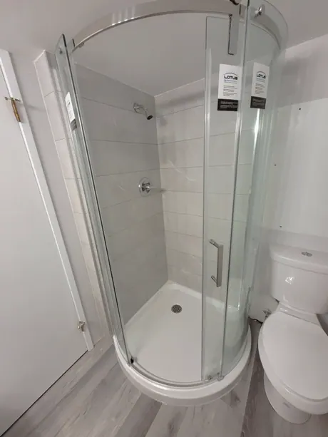 Round corner shower with curved glass and marble-look panels, Calgary
