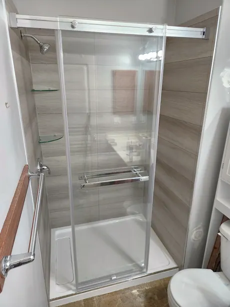 Wood-look shower enclosure with a frameless sliding door, Calgary