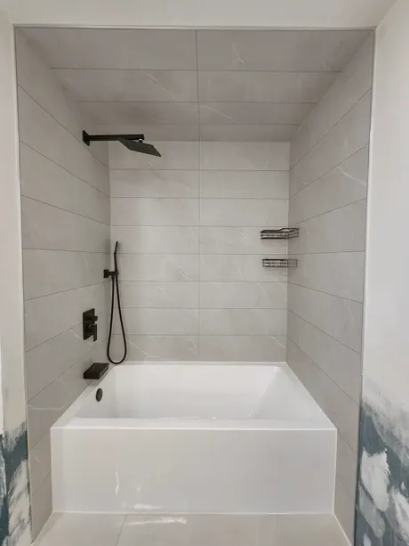 Wide view of a bathtub with grey marble-look tile-less walls, Calgary