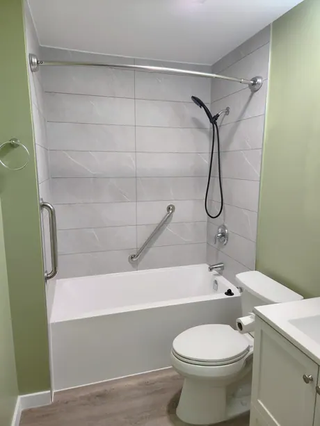 Bathtub with marble-look panels, green walls and a grab bar, Calgary