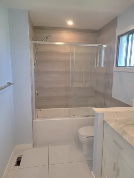 Bathtub with wood-look panels, sliding glass and a window, Calgary