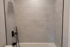 grey panels bathtub- black fixtures